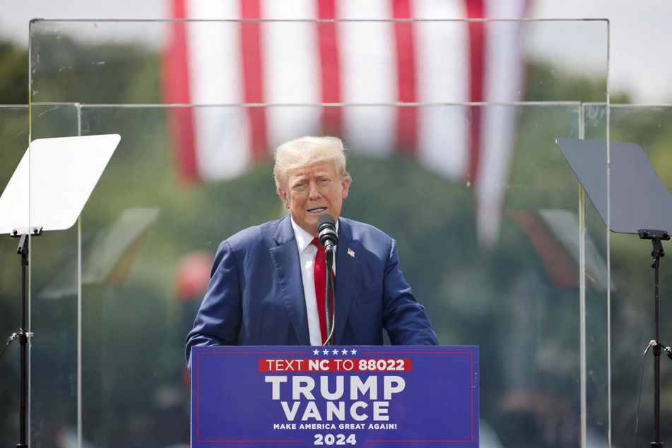 Republican presidential nominee Donald Trump speaks from behind bulletproof glass during a campaign rally at the North Carolina Aviation Museum &amp; Hall of Fame in Asheboro.