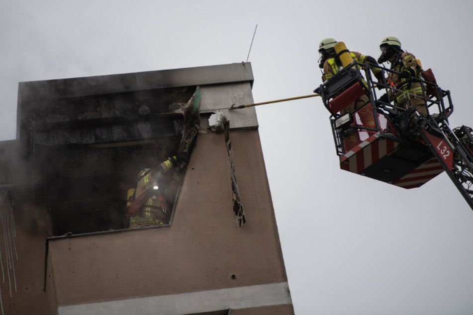 Feuerwehrleute lösen die Verkleidung am Dach eines Hauses. Die Feuerwehr musste am Dienstagvormittag einen Wohnungsbrand in Berlin-Kreuzberg löschen.