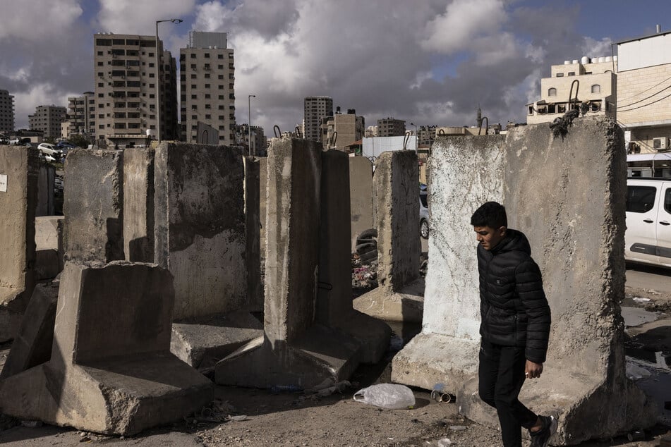 A Palestinian walks past concrete blocks at the Israeli-controlled Qalandiya checkpoint in the illegally occupied West Bank.