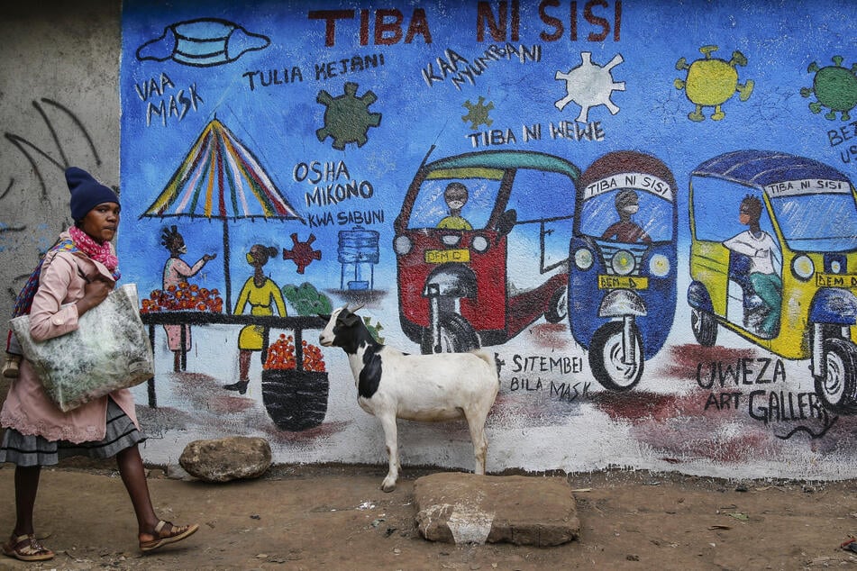 Kenia, Nairobi: Ein Frau geht an einem Wandgemälde vorbei, das über die Gefahren des Coronavirus informiert.