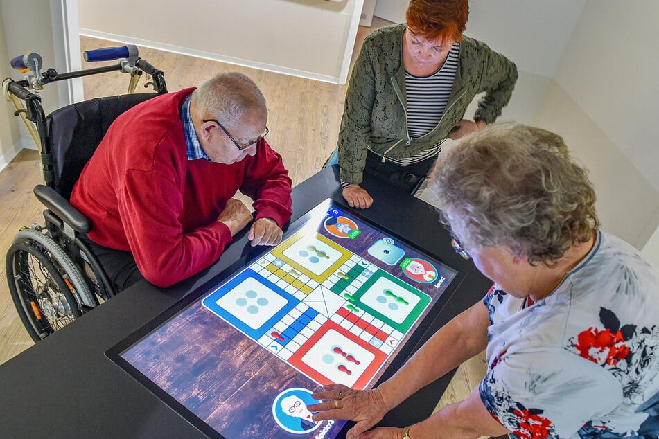 Hartmut Erhardt (81) und Annemarie Schulze (78) spielen mit Kerstin Leuteritz (53) vom ASB eine Runde "Mensch ärgere Dich nicht".