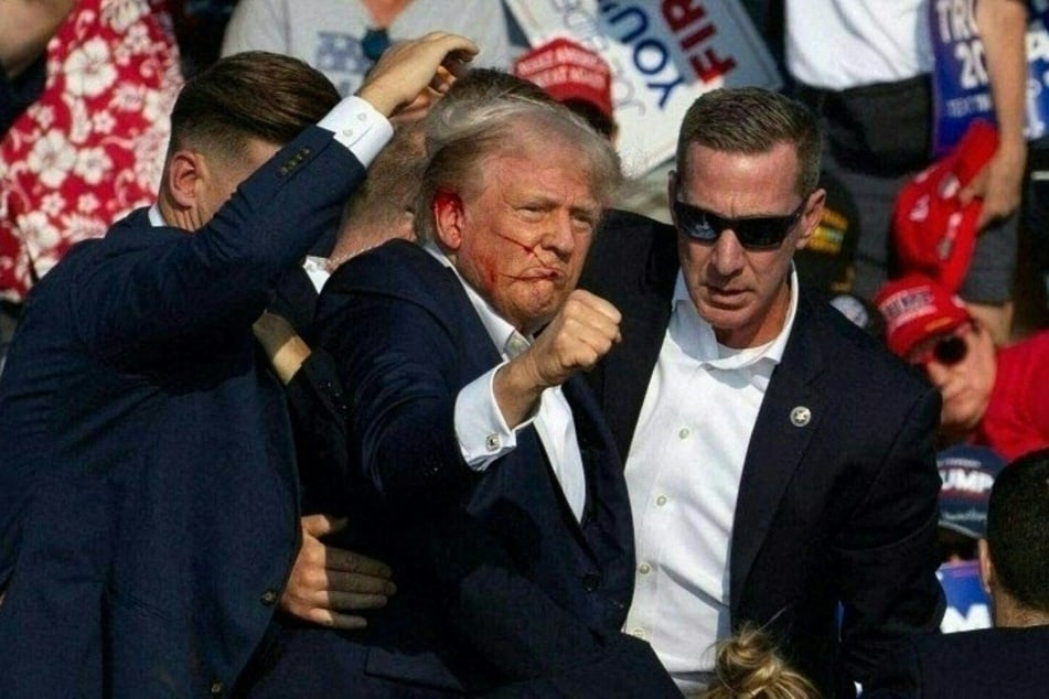 Republican candidate Donald Trump (c.) is seen with blood on his face surrounded by Secret Service agents as he is taken off the stage at a campaign event at Butler Farm Show Inc. in Butler, Pennsylvania, July 13, 2024.