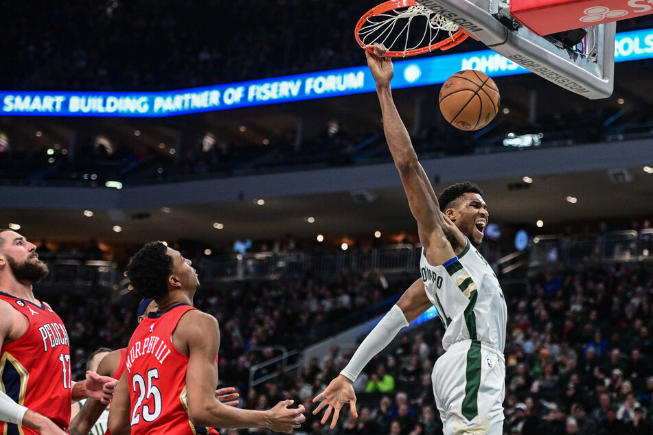 Milwaukee Bucks forward Giannis Antetokounmpo reacts after dunking a basket in the third quarter against New Orleans Pelicans center Jonas Valanciunas and forward Trey Murphy III at Fiserv Forum.