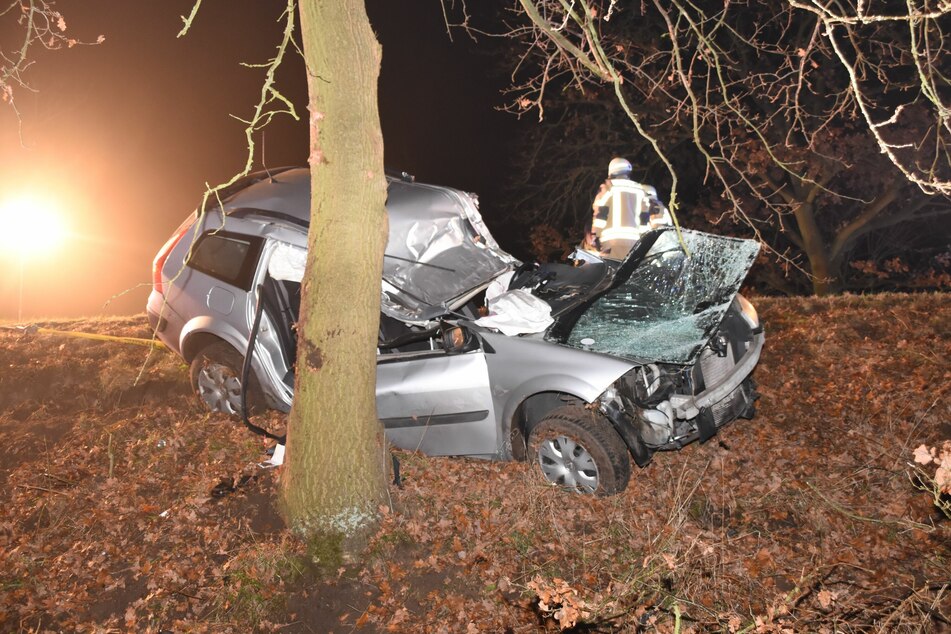 Ein Feuerwehrmann steht beim Auto am Unfallort.