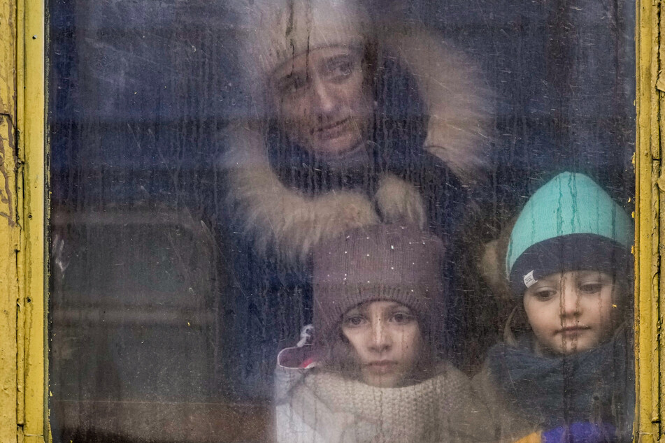 Eine Frau und zwei Kinder schauen in Kiew aus dem Fenster eines Zuges der nach Lwiw fährt.