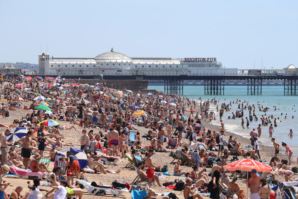 Eine große Menschenmenge verbringt den sonnigen, heißen Tag an einem Kieselstrand in Brighton.