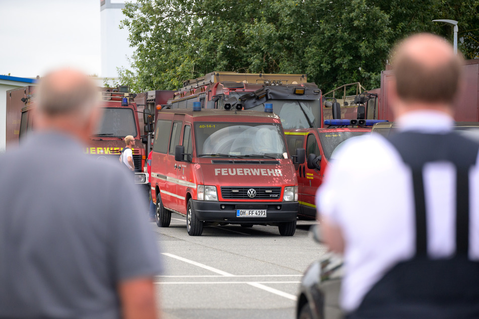 Feuerwehrleute schauen auf ihre verrußten und beschädigten Einsatzfahrzeuge.