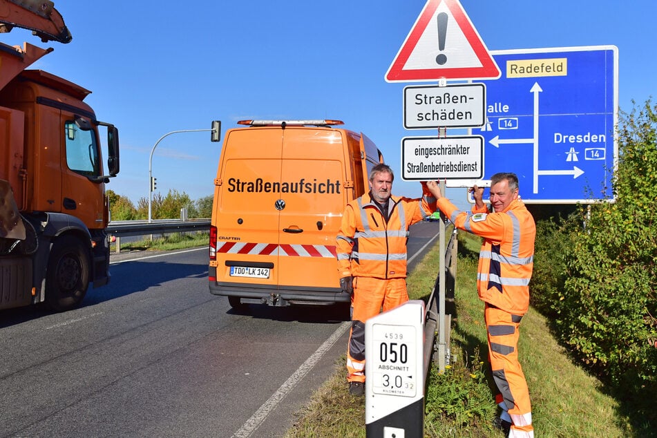 Nordsachsens Landrat Kai Emanuel (parteilos, r.) bringt mit Bernd Scheffler von der Straßenmeisterei das Protest-Warnschild an der S 1 bei Radefeld an.