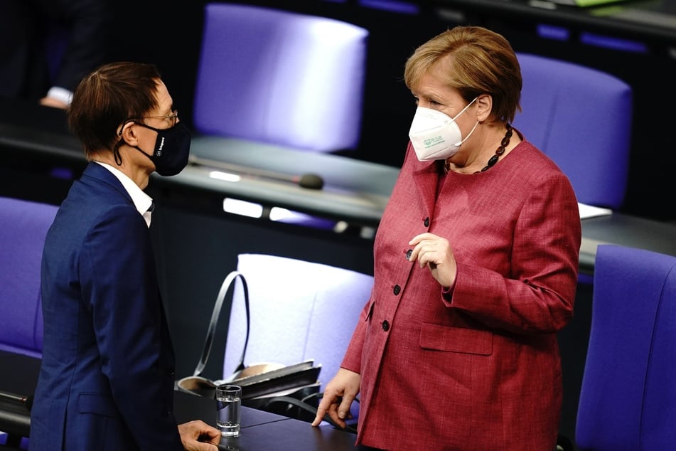 Bundeskanzlerin Angela Merkel (CDU) und der Abgeodnete Karl Lauterbach (SPD) unterhalten sich mit Mund-Nasenbedeckung vor der Sitzung des Bundestages am Donnerstag.