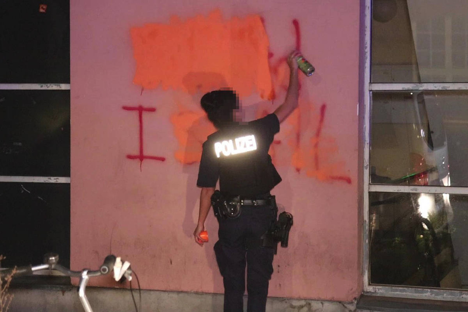 Eine Polizistin überdeckt notdürftig eine der vielen Hassparolen an den Häuserwänden mit Sprühfarbe.