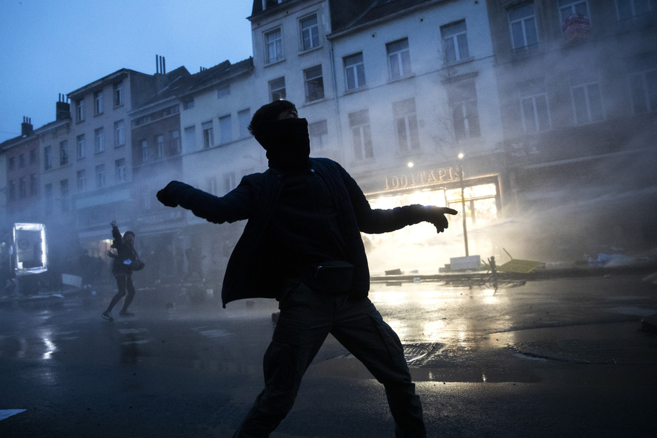 Ein Demonstrant wirft Steine in Richtung von Polizeibeamten