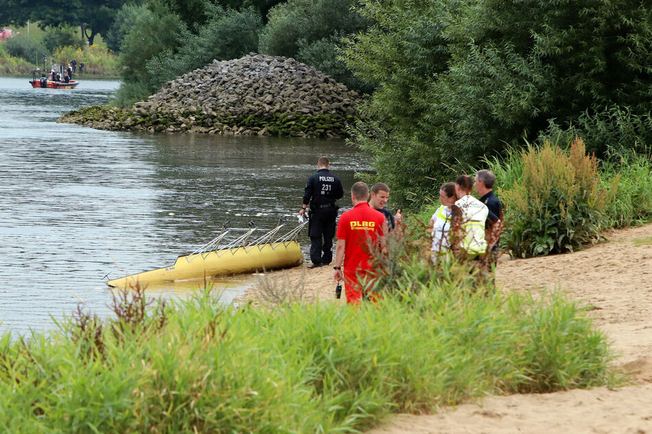 Rettungskräfte der DLRG (Deutsche Lebens-Rettungs-Gesellschaft) und Polizisten stehen am Ufer der Weser.