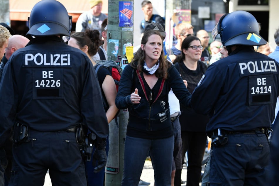 Menschen beobachten vom Straßenrand, wie die Polizei die Kreuzung Torstraße/Friedrichstraße räumt bei einer Demonstration gegen die Corona-Maßnahmen.