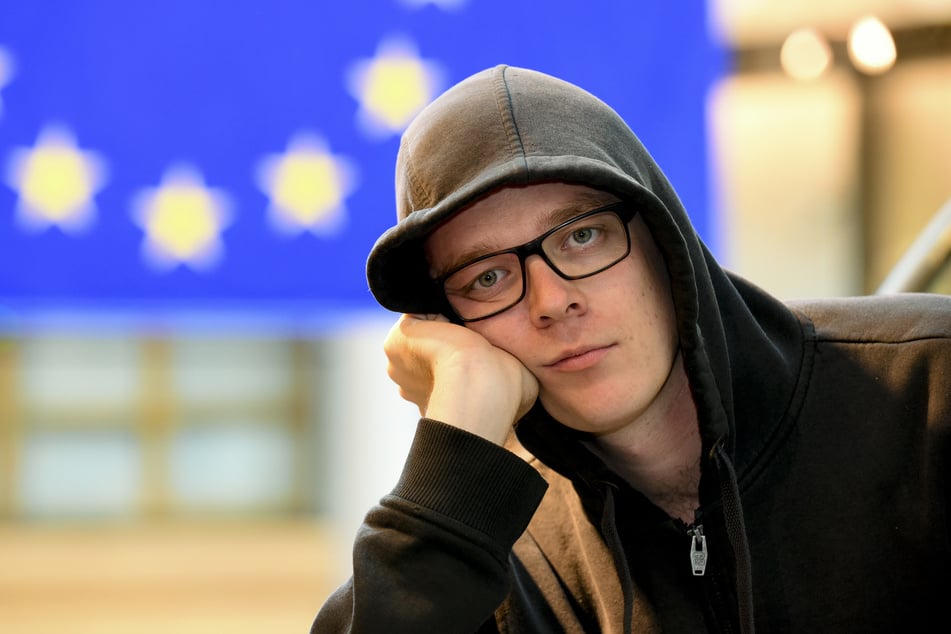 Nico Semsrott (35) sitzt gelangweilt vor einer Europa-Flagge. (Archivbild)