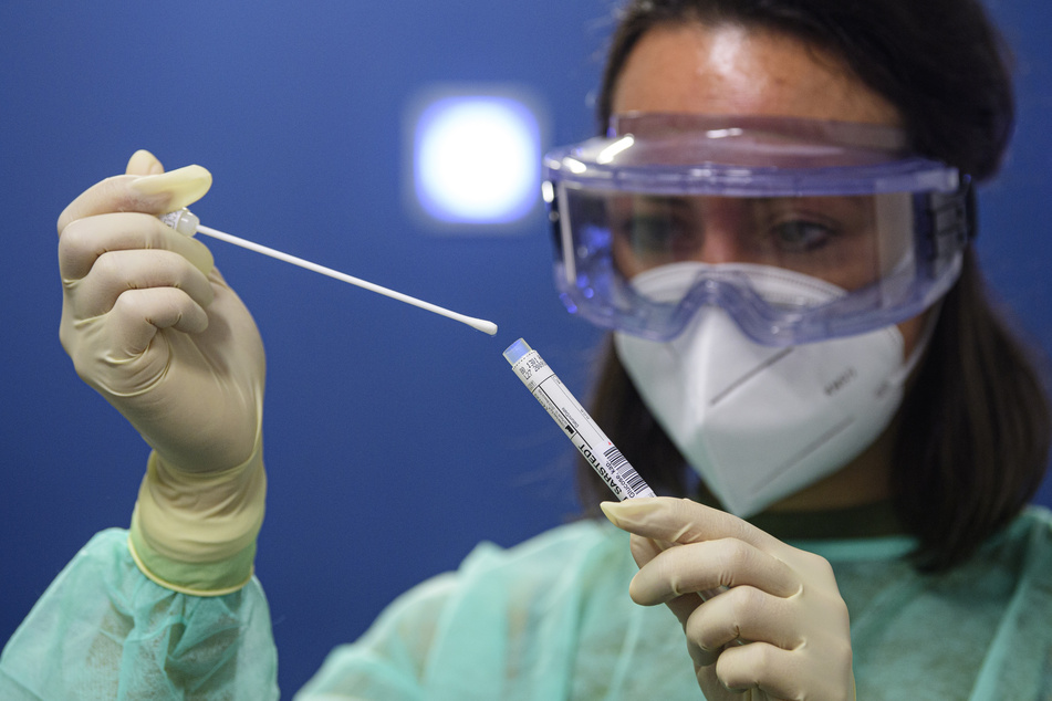 Eine Ärztin hält in einer Corona-Teststation einen Abstrich für einen Coronavirus-Test in den Händen.