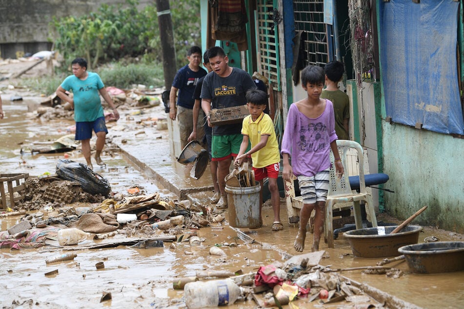 Einwohner der philippinischen Hauptstadt Manila müssen zwischen den Trümmern ihre verbliebenen Besitztümer einsammeln.