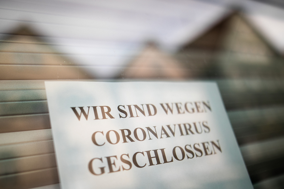 Ein Zettel weist Kunden am Schaufenster eines Geschäfts über die vorübergehende Schließung hin.