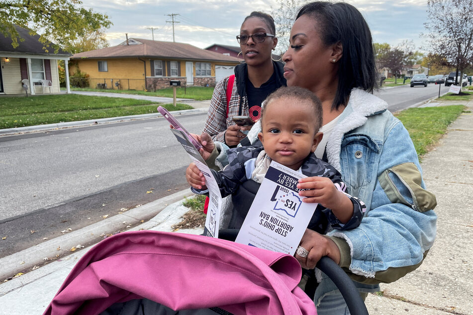 Rhiannon Carnes, executive director and co-founder of the Ohio Women's Alliance, with her 1-year-old daughter Note, and organizer Lena Collins prepare to knock on doors in Columbus to speak with voters about the state's upcoming referendum on abortion rights.