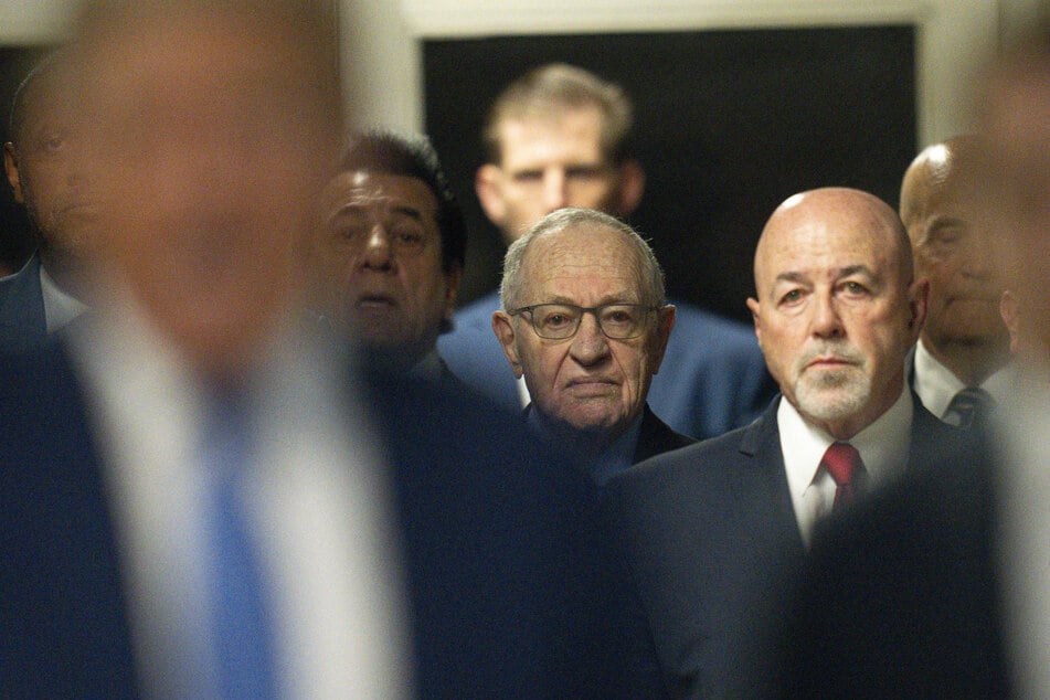 Former New York City Police Commissioner Bernard Kerik (r.) and attorney Alan Dershowitz listen as Donald Trump speaks to the media after arriving for court during his trial for allegedly covering up hush money payments on May 20, 2024.