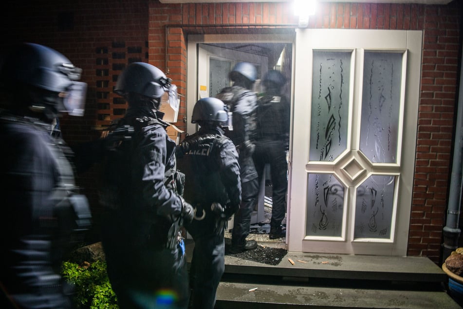 Einsatzkräfte der Polizei stürmen ein Haus, um es nach Verdächtigen zu durchsuchen.
