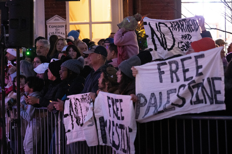 Protesters chant and hold banners at a Christmas tree lighting attended by President Joe Biden on Friday.