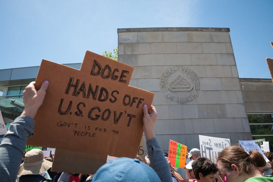 Demonstrators raise signs during a "Sick Of It" rally against the Trump administration's health care policies and cuts in front of the National Institutes of Health on May 10, 2025, in Bethesda, Maryland.
