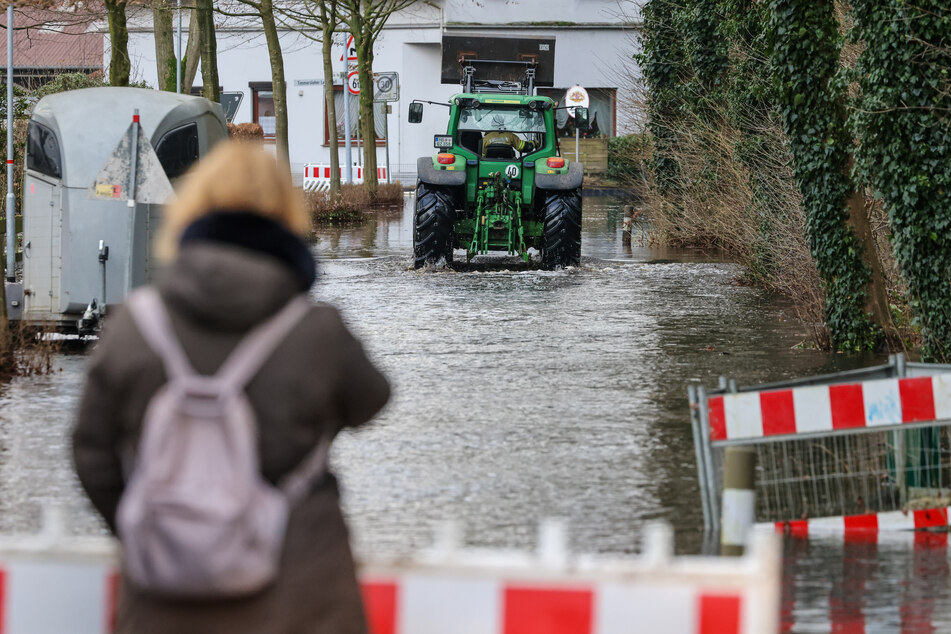 Lilienthal: Ein Traktor fährt auf einer überfluteten Wohnstraße an der Wörpe.