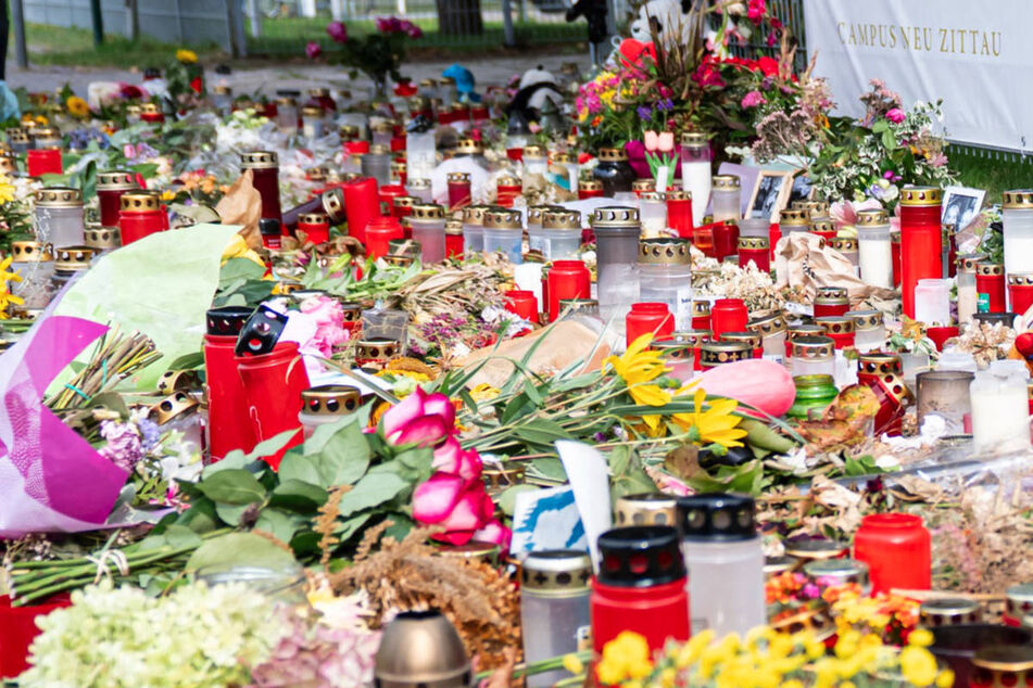 Vor dem Campus liegen unzählige Blumen und Kerzen zum Gedenken an die Toten.