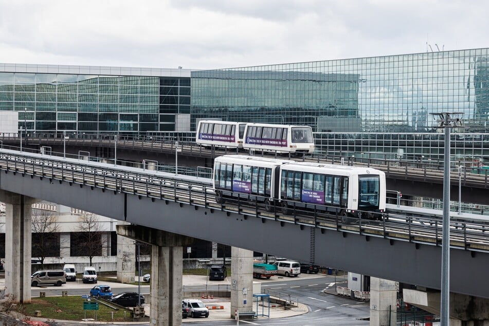 Eine neue Sky-Line-Bahn, zu sehen im Vordergrund, fährt am Frankfurter Flughafen parallel zu einer alten Bahn.