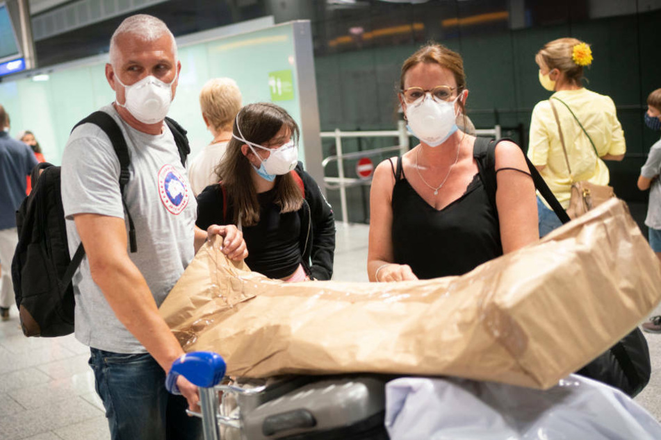 Der Arzt Andreas Mösbauer aus Neu-Isenburg (l) verlässt zusammen mit Jessica Becker (r) nach seiner Ankunft von einem Urlaub auf Mallorca ein Terminal des Frankfurter Flughafens.