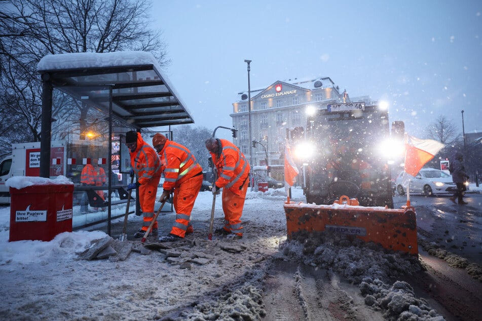 Mitarbeiter der Stadtreinigung Hamburg räumen eine Bushaltestelle am Stephansplatz.