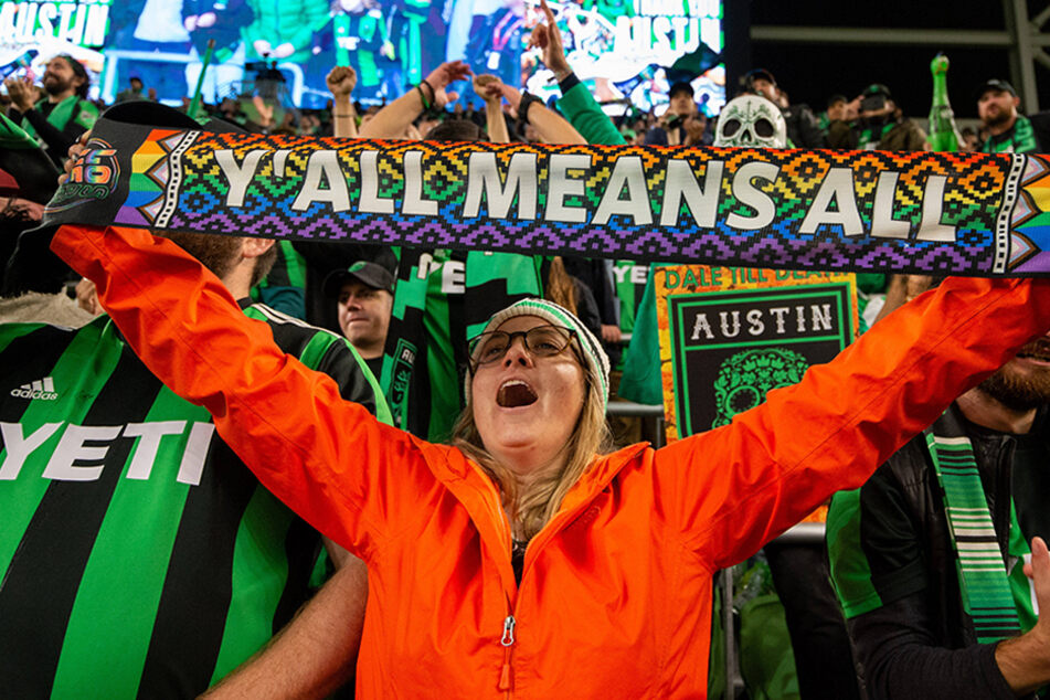 An Austin FC fan holds up a "y'all means all" scarf following the team's win over Sporting Kansas City on November 3 at Q2 Stadium in Austin, Texas.