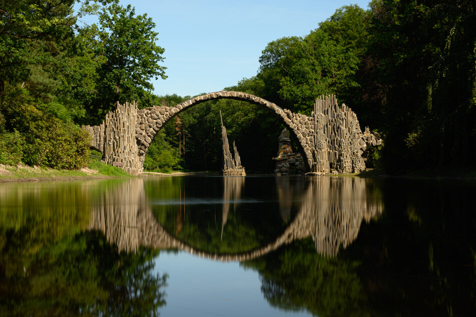 Die Rakotzbrücke bildet einen steinernen Kreis mit dem Wasser im See des Azaleen- und Rhododendren-Parks in Kromlau im Landkreis Görlitz.
