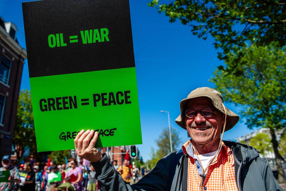 A protester holds a sign by Greenpeace during an International Workers Day rally in Amsterdam, Netherlands, on May 1, 2026.