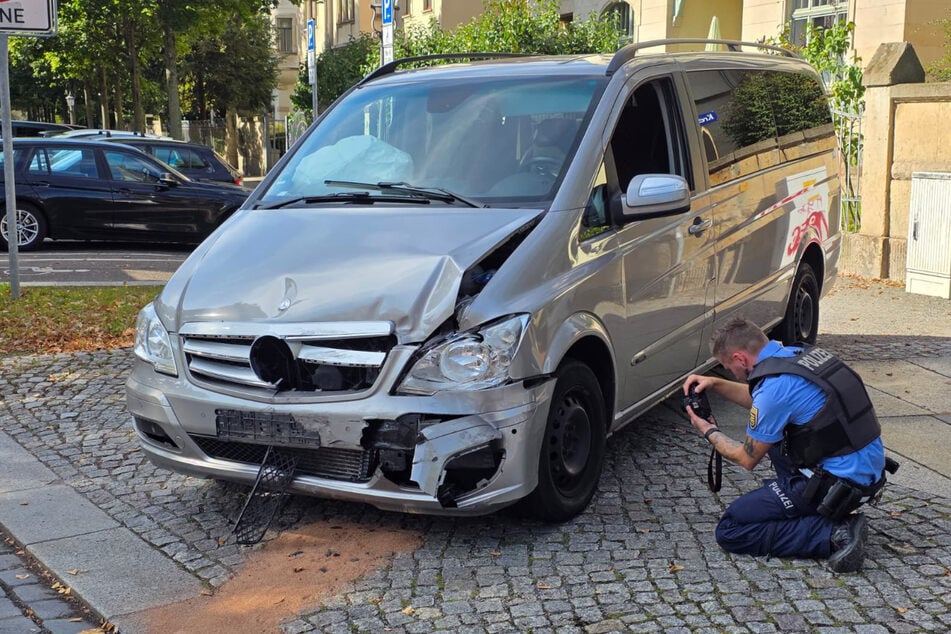Crash in Striesen: ein Polizist vor einem beschädigten Kleintransporter von Mercedes.