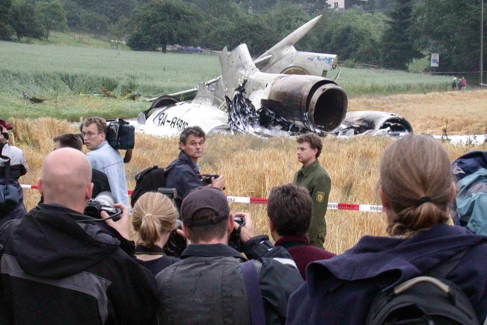 Überlingen, 2. Juli 2002: Das Heck des abgestürzten russischen Flugzeugs Tupolew Tu-154 der Bashkirian Airlines liegt in einem Kornfeld, während Journalisten hinter einer Absperrung stehen.