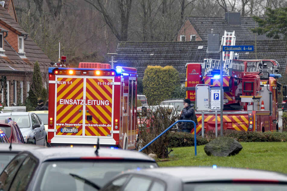 Einsatzkräfte von Polizei und Feuerwehr stehen neben dem Haus in der Cäcilienstraße.