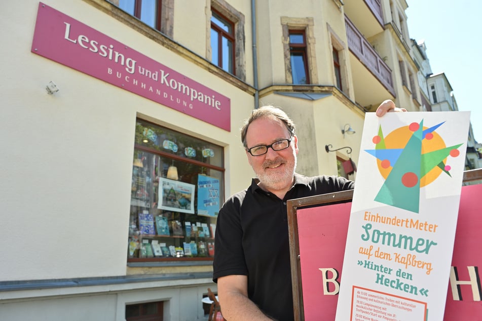 Mitorganisator Klaus Kowalke steht mit einem "100-Meter-Sommer"-Plakat vor Buchhandlung "Lessing und Kompanie".