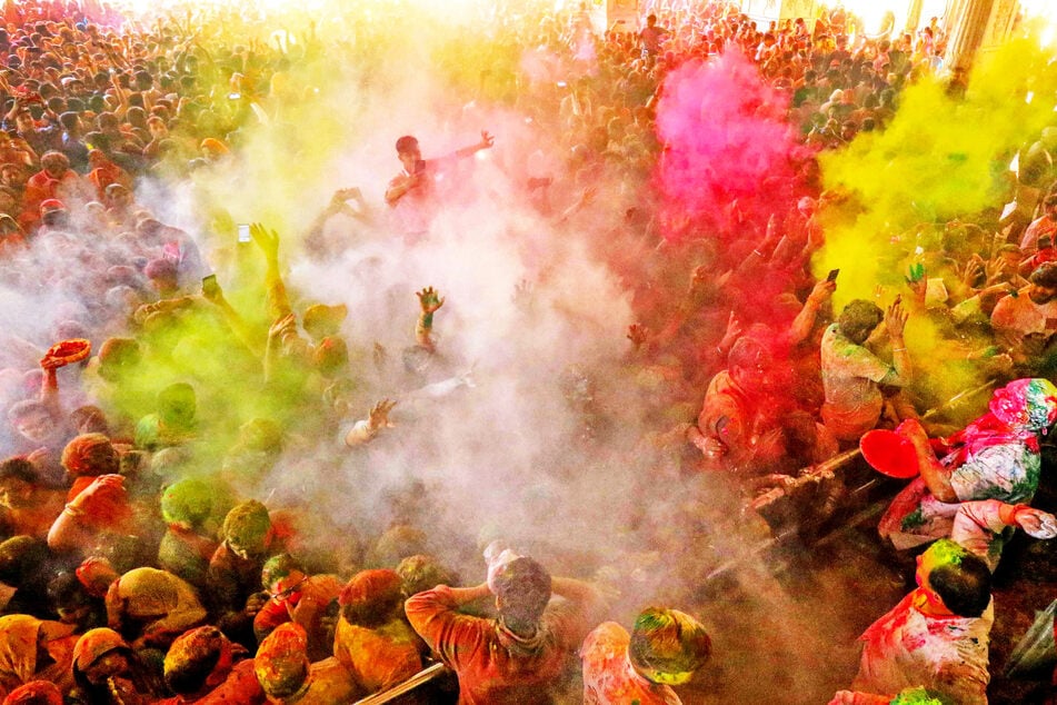 Anhänger werfen während des Holi-Festes im Govind Dev Ji-Tempel in Jaipur in Indien mit buntem Farbpulver.