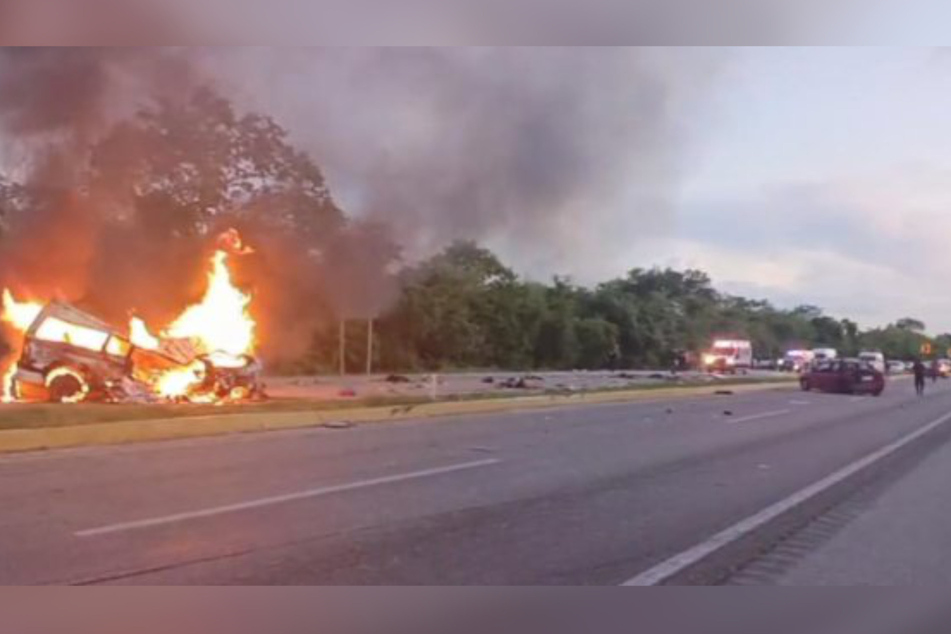 Behörden veröffentlichten eine Aufnahme vom Unfallort. Im Bild ist eines der beteiligten Autos zu sehen - in Vollbrand.
