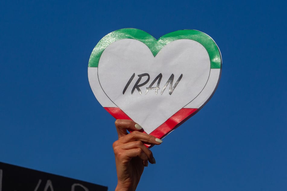 A woman holds a heart-shaped sign in the colors of the Iranian flag as protesters rally during a "No War on Iran" demonstration outside the Wilshire Federal Building in Los Angeles, California, on June 18, 2025.