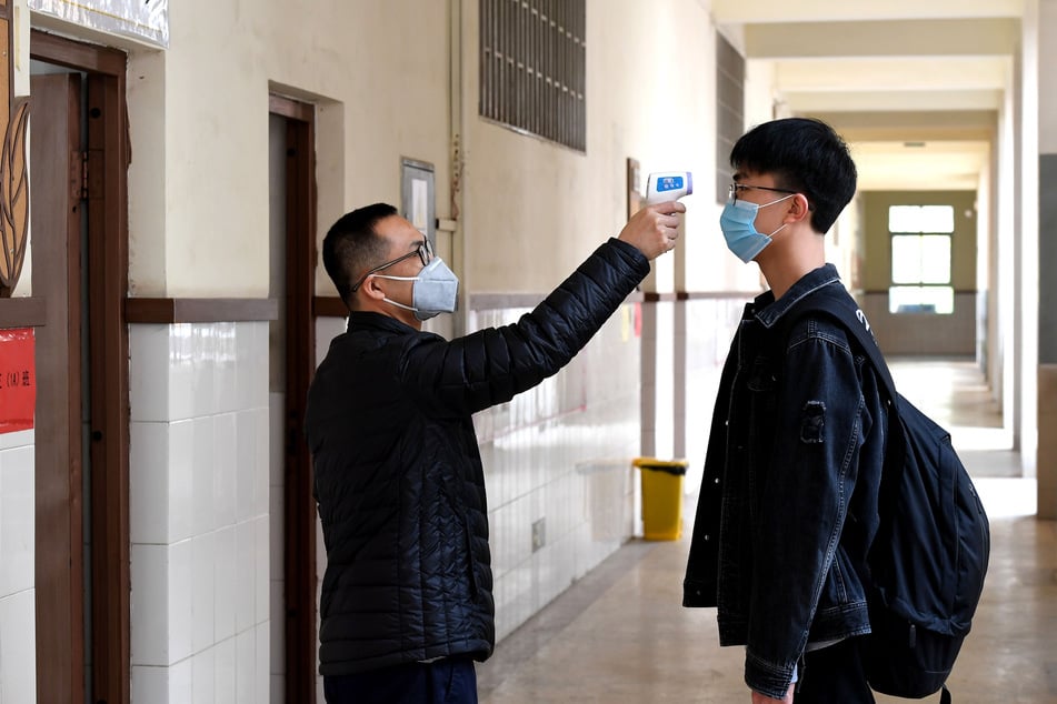 Ein Lehrer misst die Temperatur bei einem Schüler in der Schule Nr. 9 in Zhengzhou (China). Soweit soll es hierzulande jedoch nicht kommen.