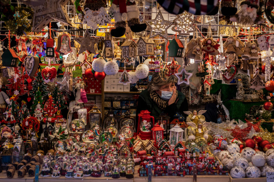 Eine Verkäuferin mit Maske wartet auf Kunden an einem Weihnachtsmarktstand auf der Plaza Mayor.