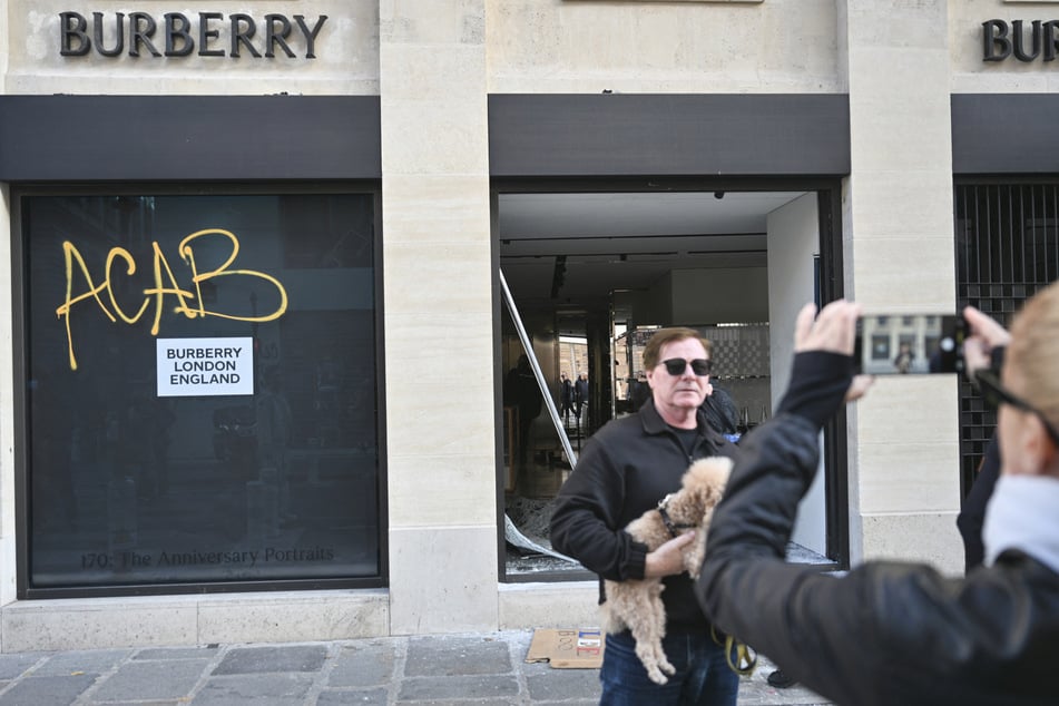 Bitte lächeln! Ein zerstörter Burberry-Laden dient als Kulisse für ein Katastrophenfoto.