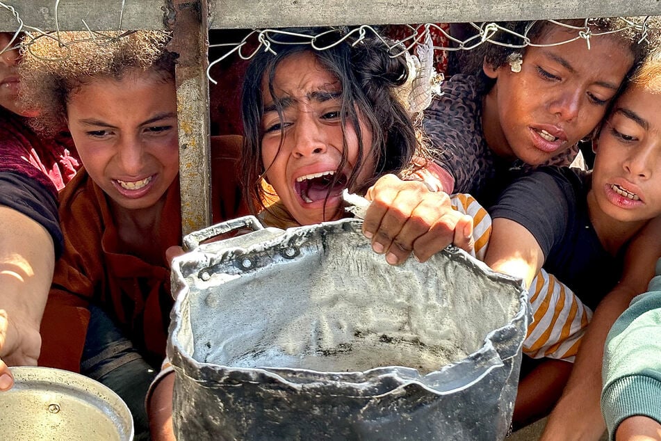 Palästinensische Kinder versuchen im Gebiet Al-Mawasi im Gazastreifen, mit ihren Töpfen Nahrungsmittel zu bekommen.