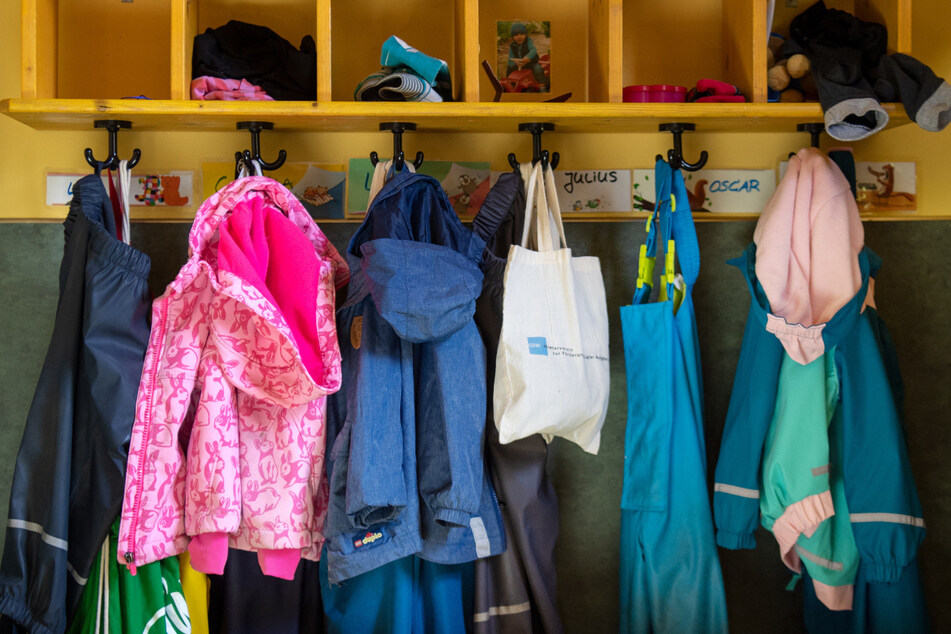 Jacken und Taschen hängen im Eingangsbereich in einem Kindergarten. Ab Montag wird es in den Kitas wieder etwas voller.