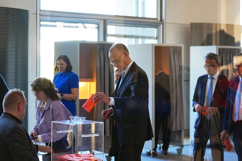 Der designierter Bundeskanzler Friedrich Merz (69, CDU, m.), gibt im Bundestag bei der Kanzlerwahl seinen Stimmzettel ab.