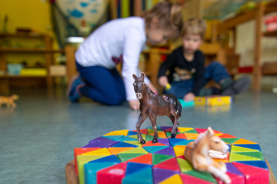Ein Junge und ein Mädchen spielen in einem Kindergarten auf dem Boden. (Symbolbild)