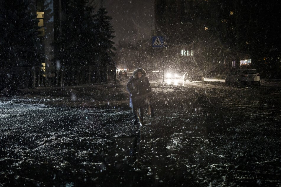 Eine Frau läuft bei Schneefall durch Kiew. Mit den schwersten Raketenangriffen seit Wochen legte Russland am Freitag erhebliche Teile der ukrainischen Stromversorgung lahm. In der von besonders vielen Raketen anvisierten Hauptstadt fielen am Freitag Licht, Wasser und Heizung aus.