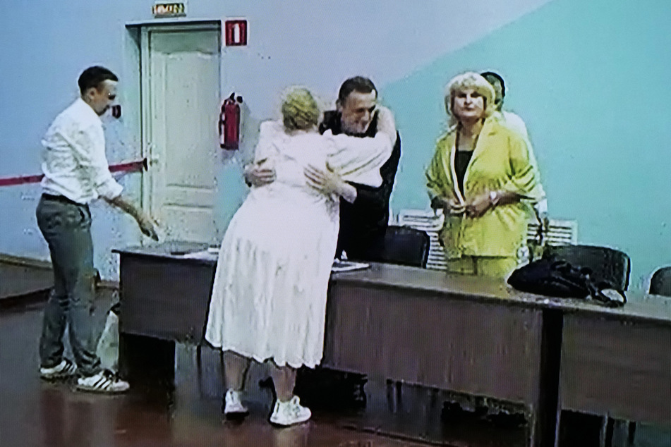 Alexej Nawalny (M.) wird nach der Urteilsverkündung von einer Anwältin umarmt.